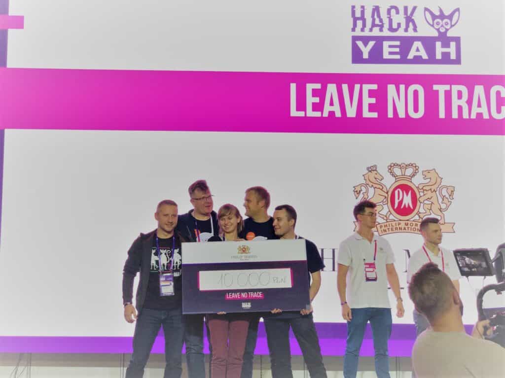 Grupowe zdjęcie zwycięskiej drużyny Deviniti na scenie hackathonu HackYeah po wręczeniu nagrody za zajęcie III miejsca w kategorii Philipp Morris International.
