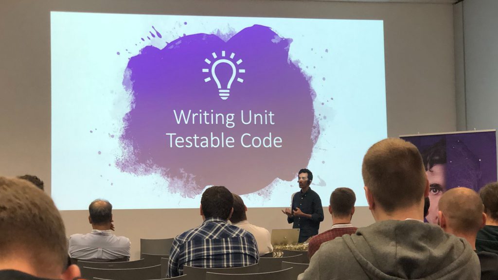 Conference room, a lecture on testing, a light bulb on the lecture screen and the inscription: Writing Unit Testable Code.
